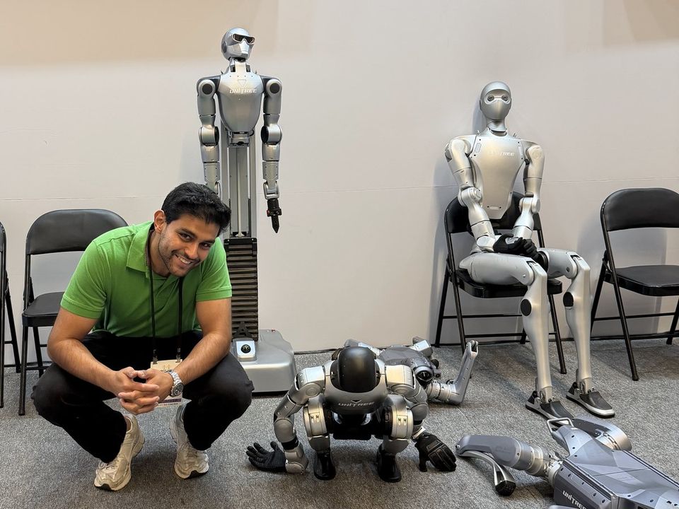 Shayaan crouching beside several humanoid robots